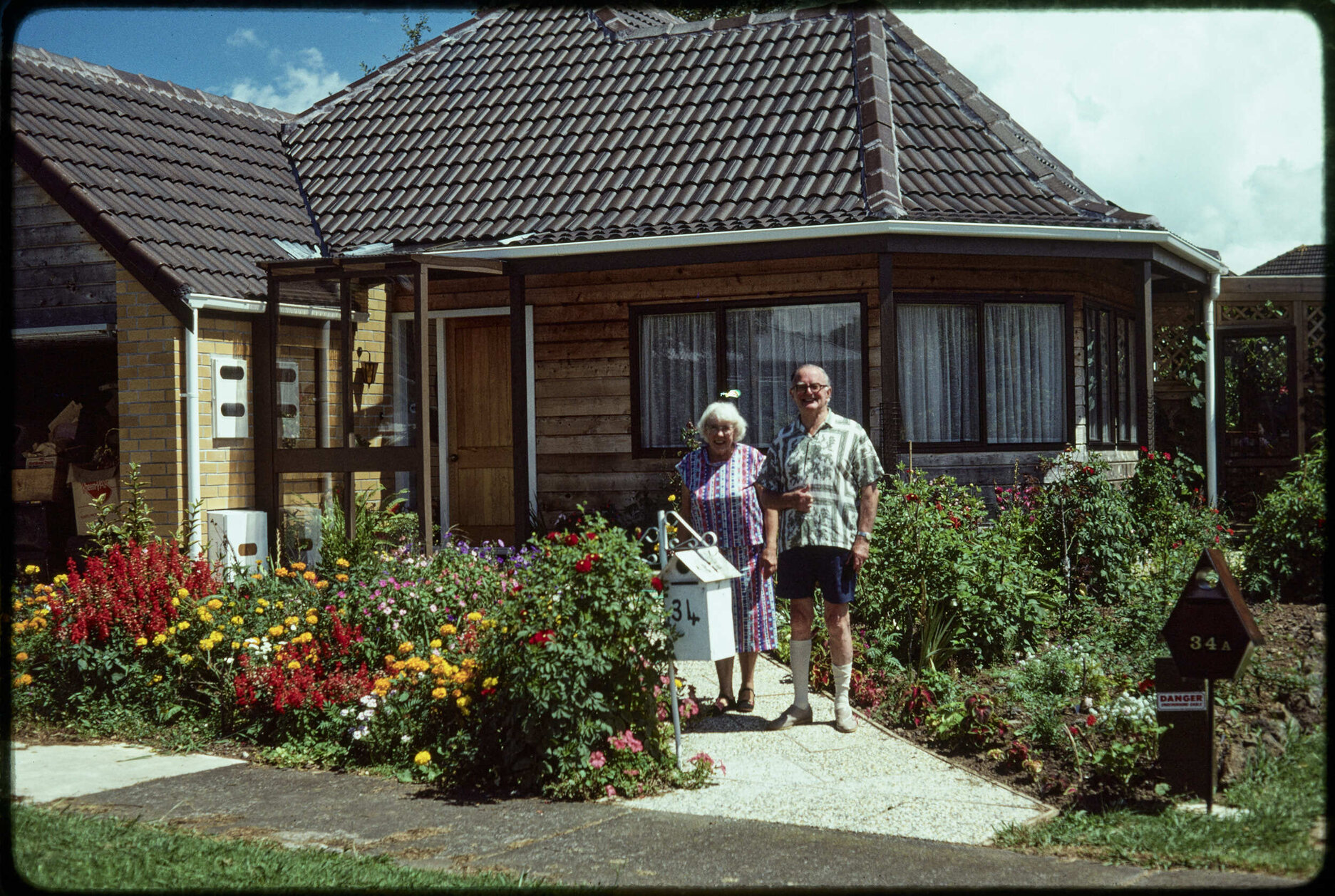 Lady Enid and Sir John Walsh, standing in front of a house