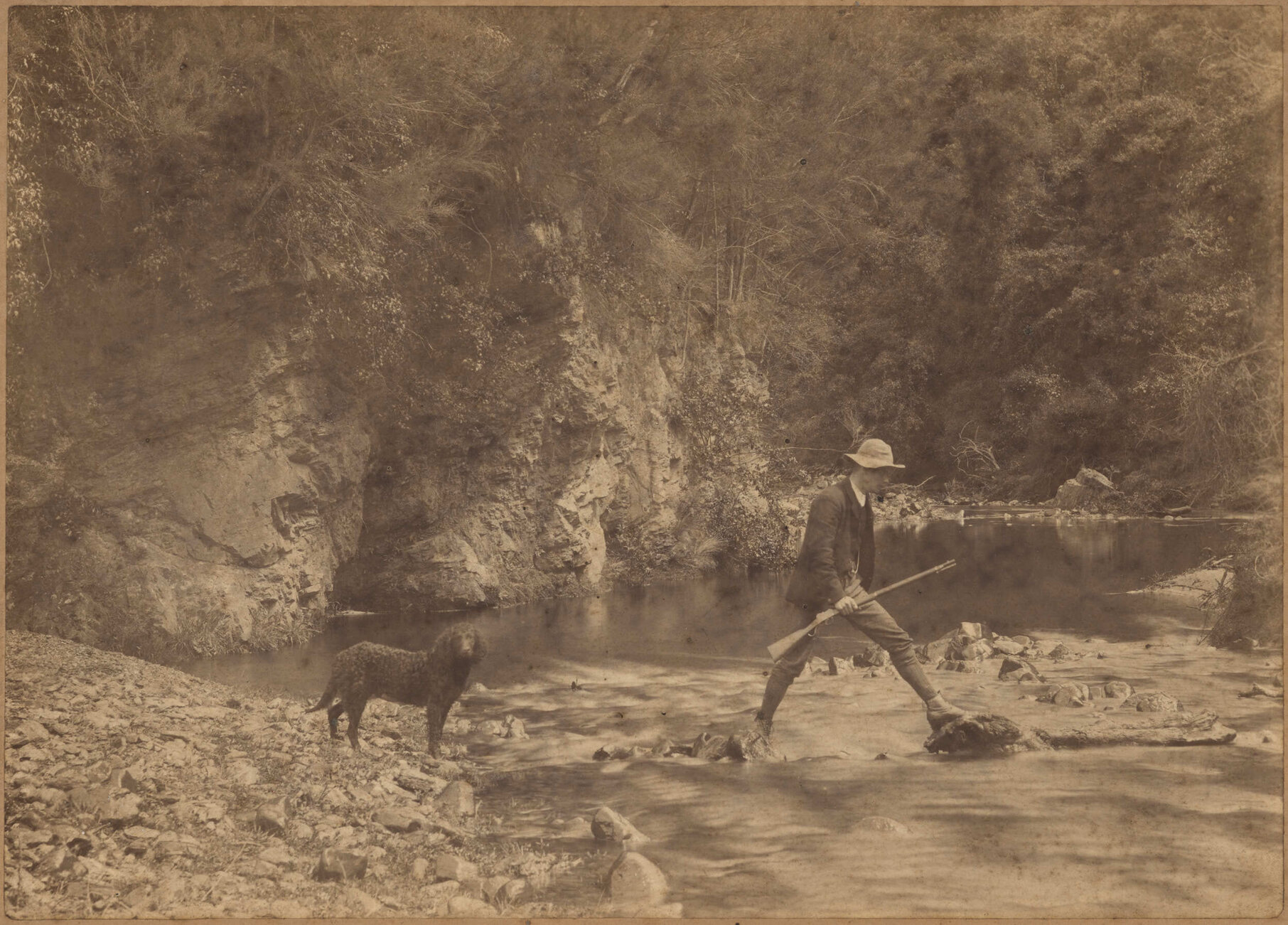 Man and dog crossing creek