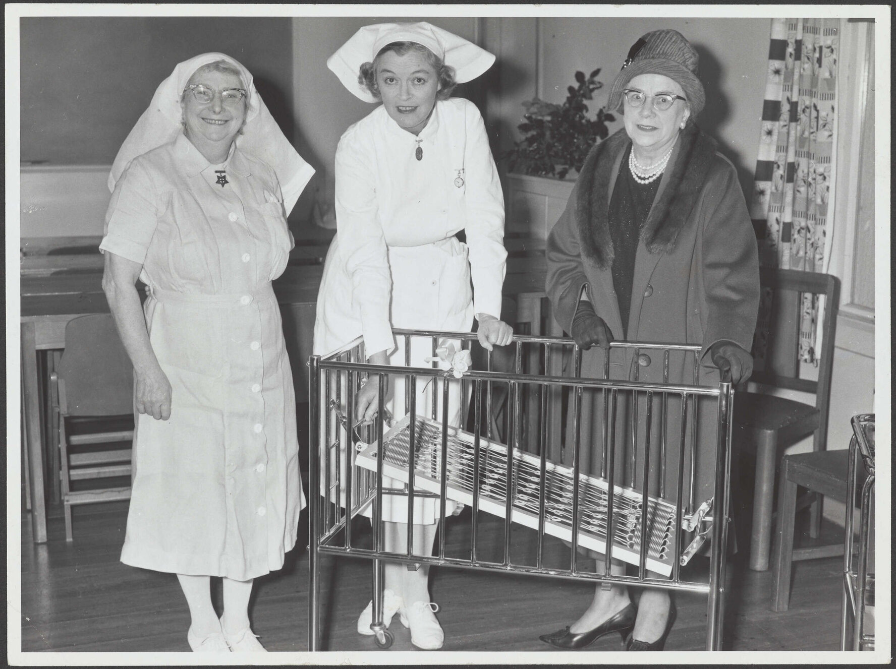 Two nurses and woman with baby cot