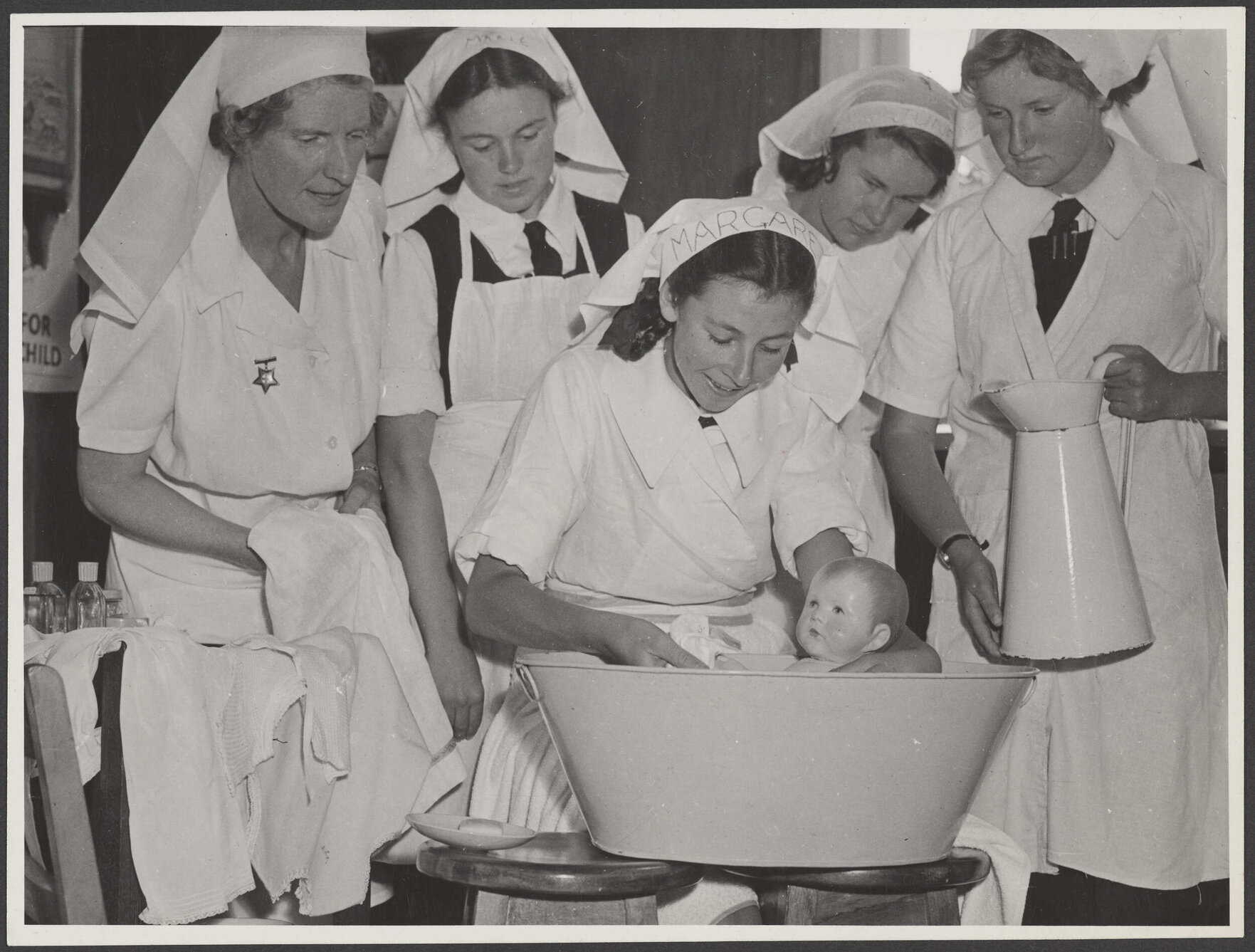 Nurse and students [?] bathing baby doll
