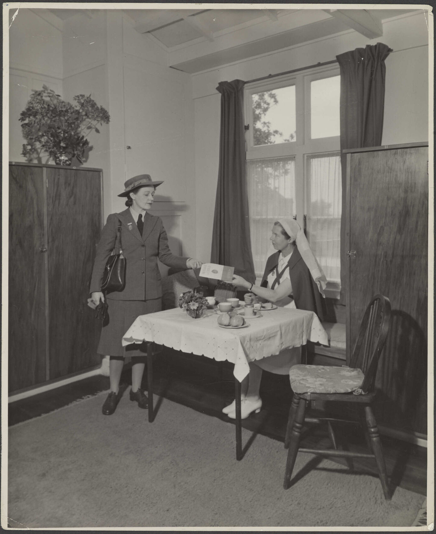 Two Plunket nurses posing with publication titled 'Woman and Child'