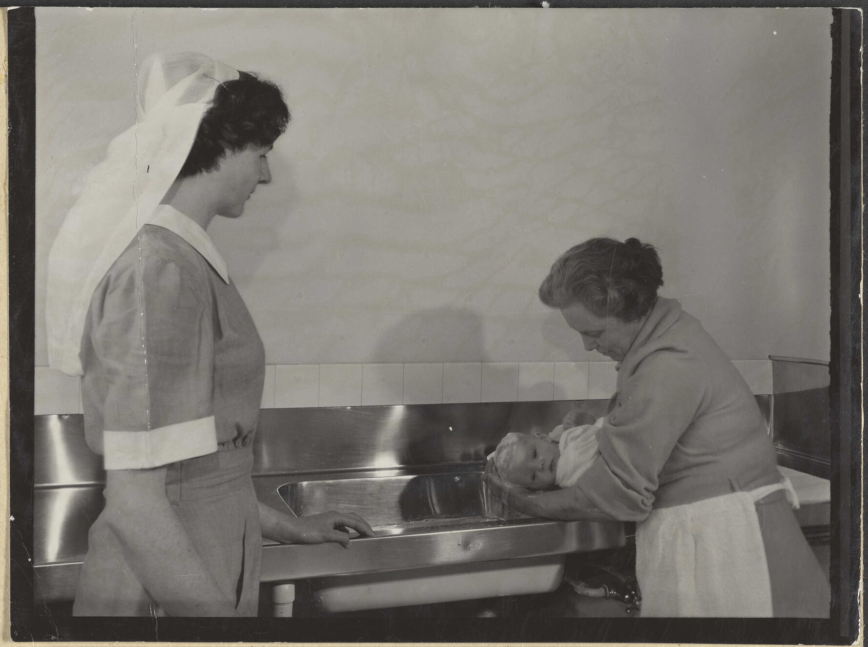 Nurse and mother [?] bathing baby