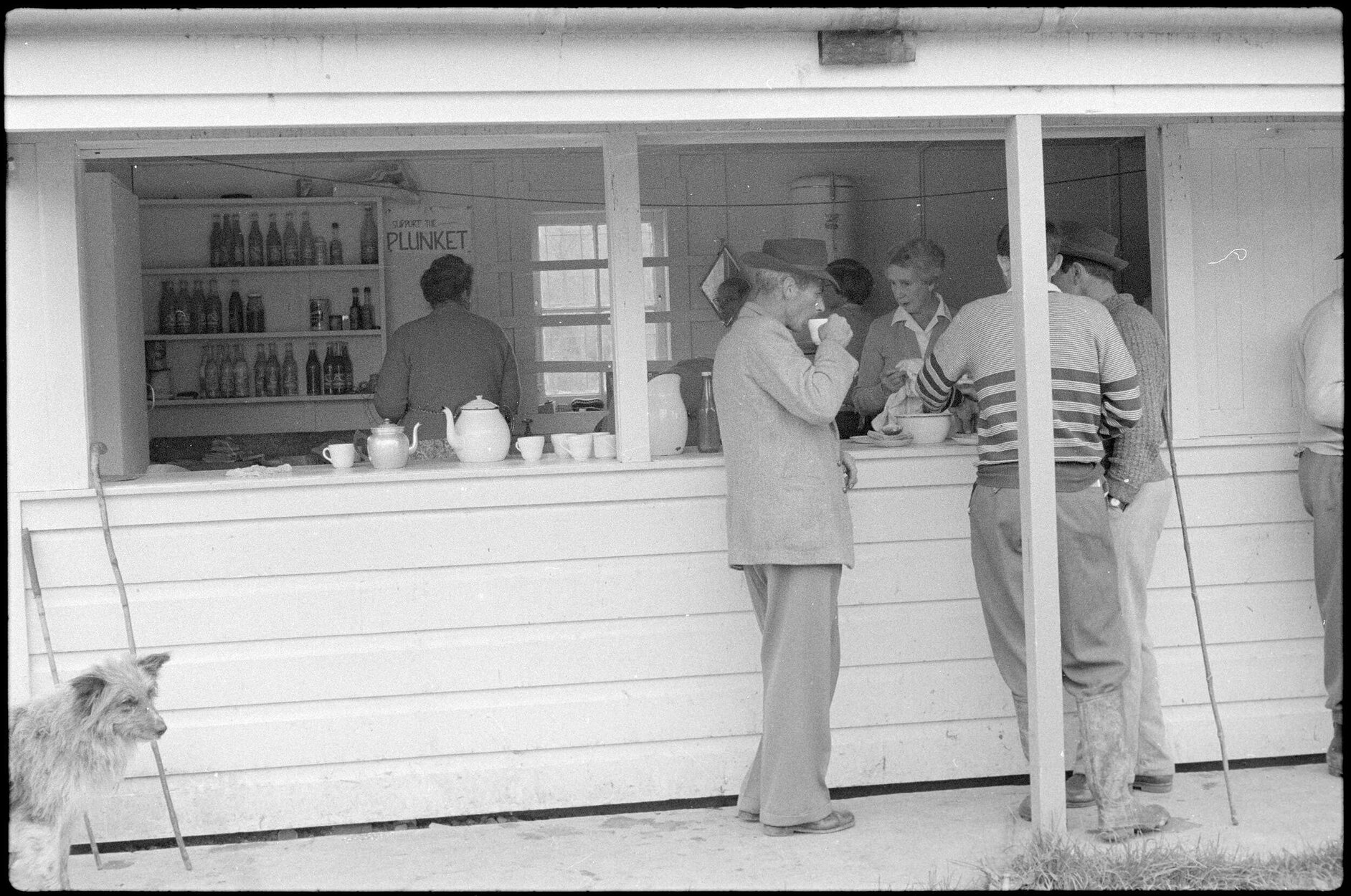 Women working in a canteen and men outside