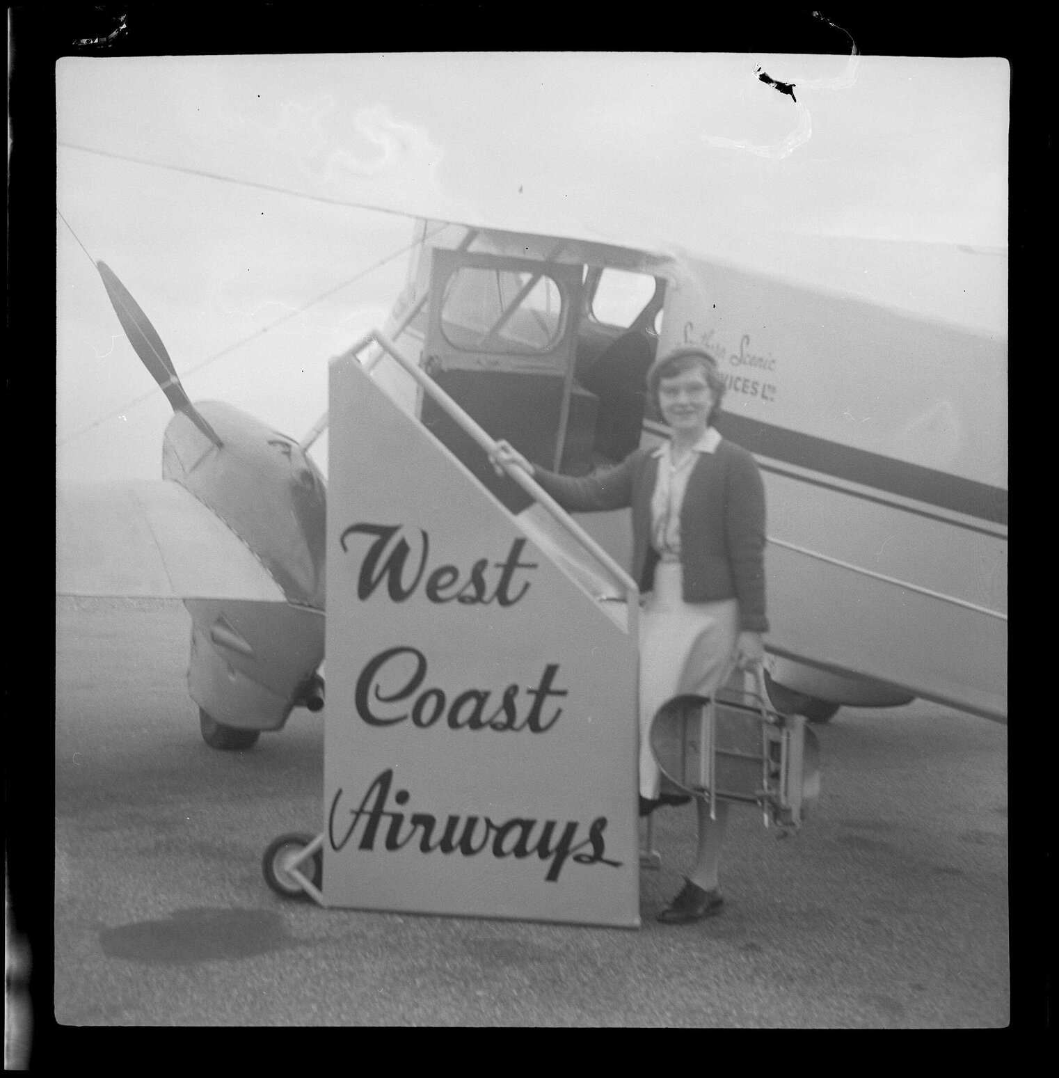Woman standing in front of a West Coast Airways plane