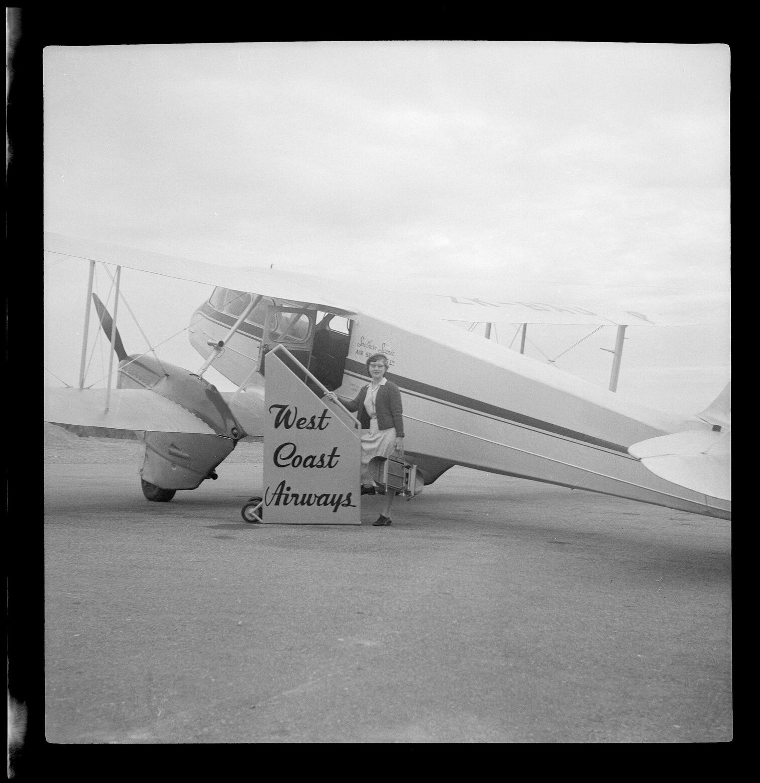Woman standing in front of a West Coast Airways plane