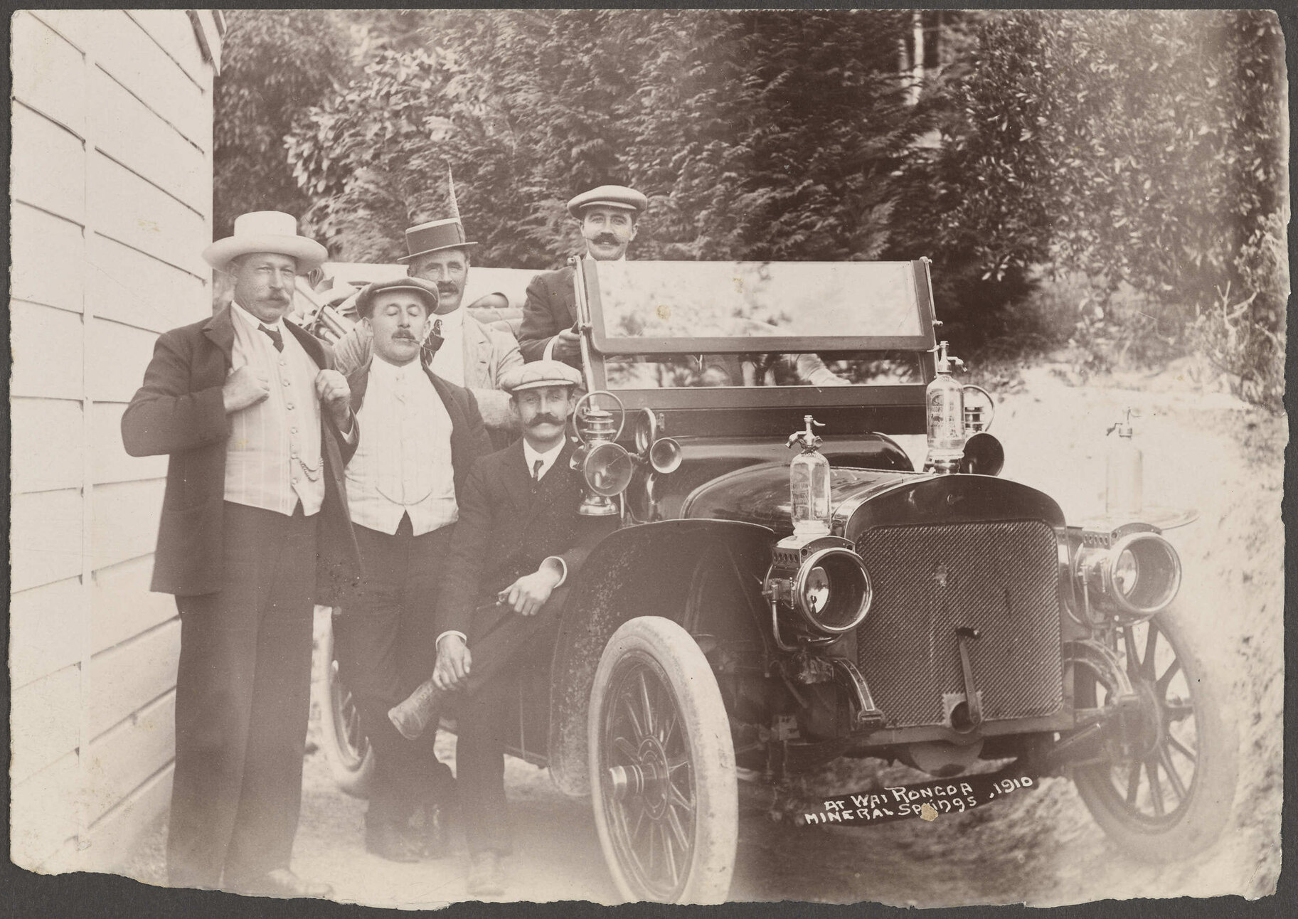 Five men sitting and standing by a car at Wairongoa Springs