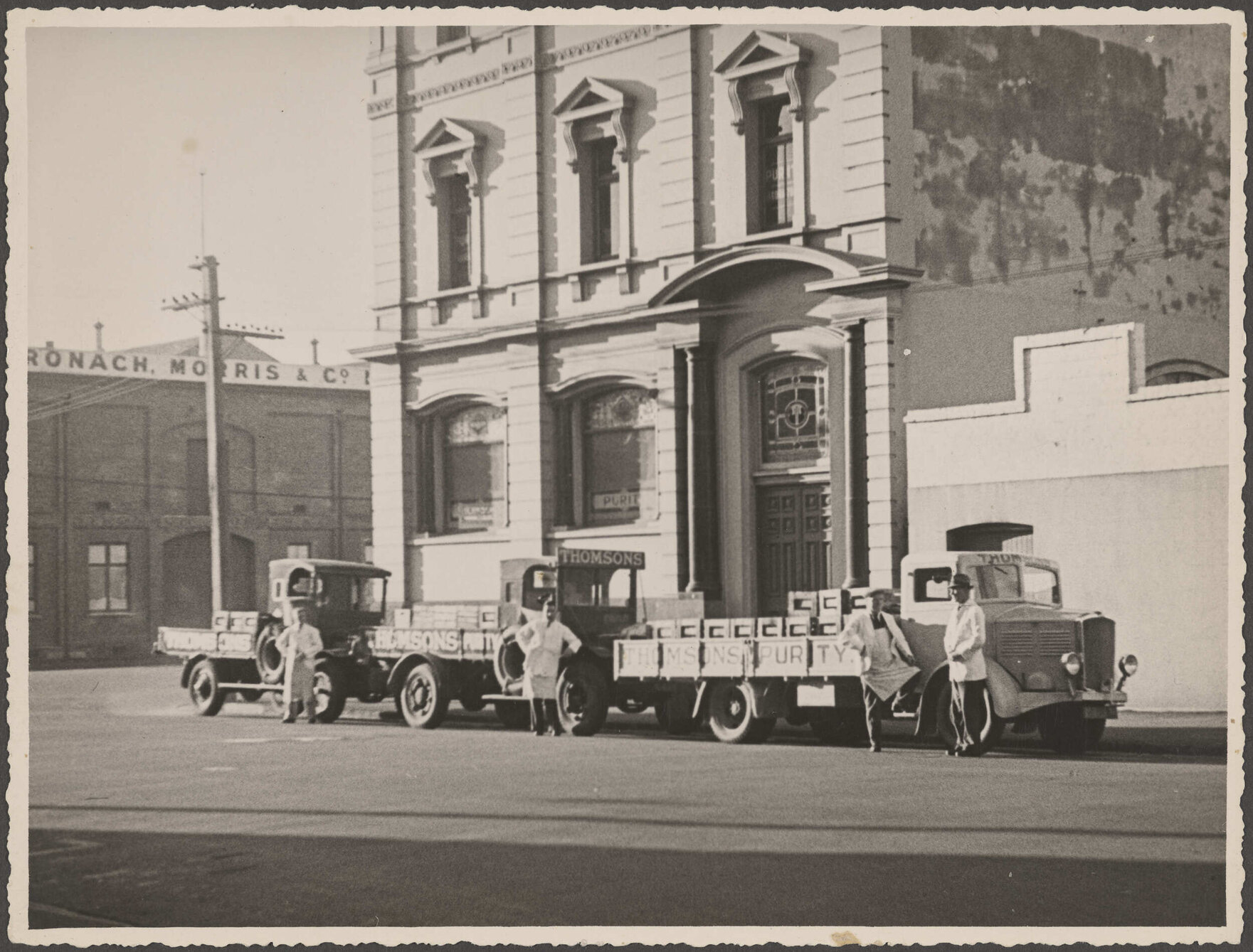 Four people and three delivery trucks outside Thomsons premises