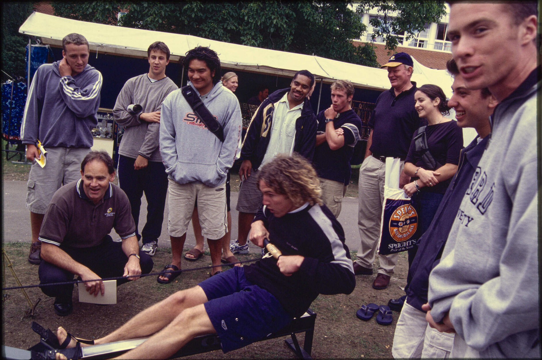 Group gathered around student using rowing machine on Union Lawn