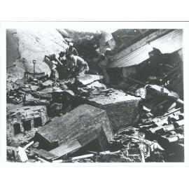 Naval men searching among ruins for bodies