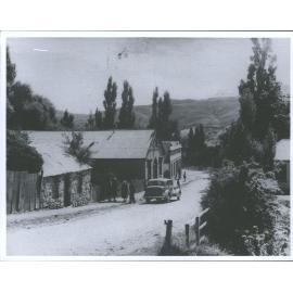 Scene in St Bathans showing people and car in the street near the Vulcan Hotel
