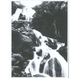 Unidentified person sitting on a rock atop a waterfall