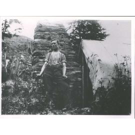 McChesney, T. (miner) outside his sack & canvas hut