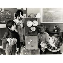 Four children with a robot made from boxes and other materials