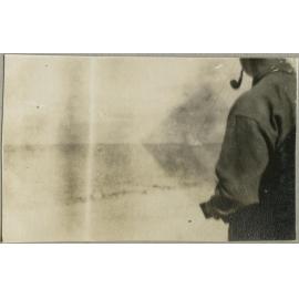 Man with a pipe standing on a shore