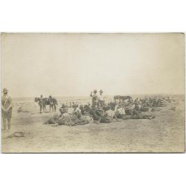 A large group of men, mostly lying or seated on the ground