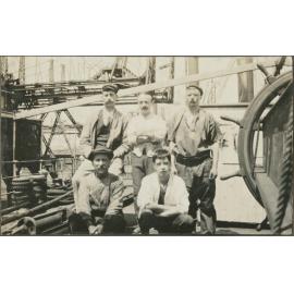 Group of five men next to the wheel on a ship
