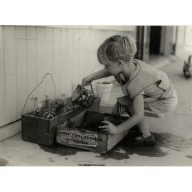 'Child playing with watering can'