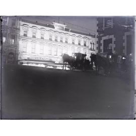 Brown Ewing and Company building and horse-drawn cabs at night, looking from Liverpool Street across Princes Street, Dunedin