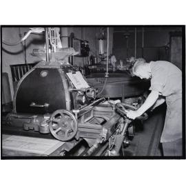A young man at a machine, in the process of printing a 'Shell Road Maps New Zealand' book, Coulls Somerville Wilkie, Crawford Street, Dunedin