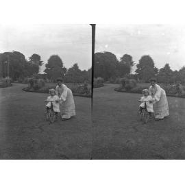Emily on bike in driveway, held by Ethel