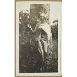James Courage in drag, standing against a tree