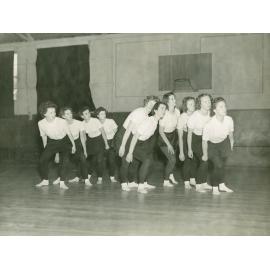 Ten dancers, leaning over, looking right