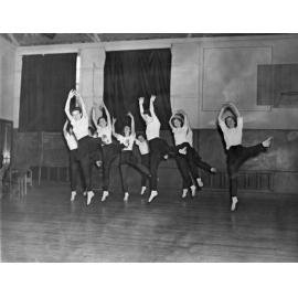 A group of ten dancers leaping