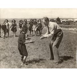 Smithells playing with boy, while group of girls watch in background.
