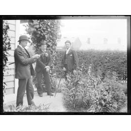 Jim Manson (centre) and two unidentified men in a garden, next to a house