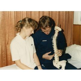 Two people looking at model of spinal cord