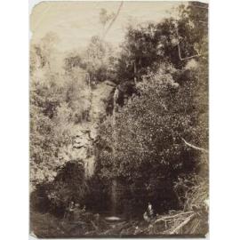 Three people at the foot of a waterfall