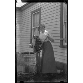Woman pumping water into a barrel