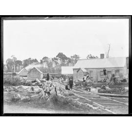 Scene showing railway, wooden buildings, children, and cleared land