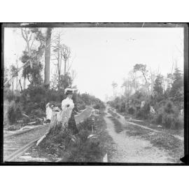 Scene at Invercargill [?], showing a road, timber tramway tracks, and a woman