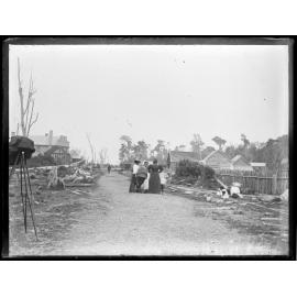 Scene [at Colac Bay] showing a road, tramway line, buildings, and a group of women and children