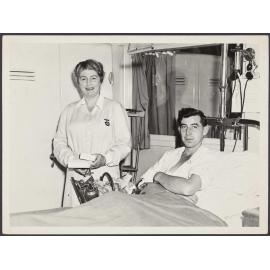 St John attendant standing next to a patient in a hospital bed