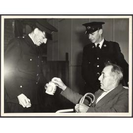 'Mr T.J. Moynihan, a patient of Parkside Hospital, handing a donation to Ambulance Drivers Messrs. M.V. Jane and J.R. Wilson when he arrived at the School of Physiotherapy'