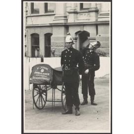 Two men in uniform next to a St John Ambulance Association cart