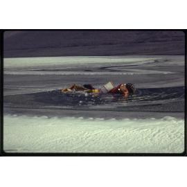 Tractor with trailer load of ice breaks through thin new ice on lake