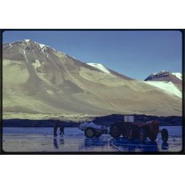 Cutting ice for ice melter, with Mt Odin and Jeremy Sykes Glacier in background'.