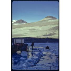 Cutting ice early winter for station ice melter, station seen in mid-distance
