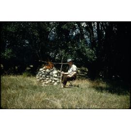 Ernie Webber beside a campfire