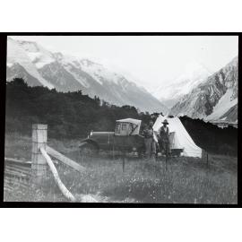 Two people standing next to a car at a camp in the Hooker Valley