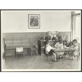 Preschool children in classroom with metal-framed chairs and tables