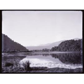 View over a lake to distant snowy peaks, Westland