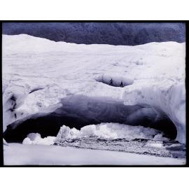 Two people standing on an arch of glacial ice next to a stream, Westland