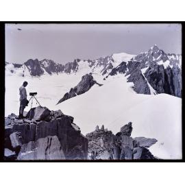 Person standing next to camera on tripod, looking towards Douglas Peak 