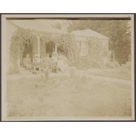 Family group seated in front of house
