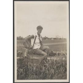 Unidentified woman sitting on a fence