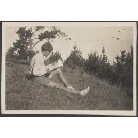 Person sitting on grassy bank, reading